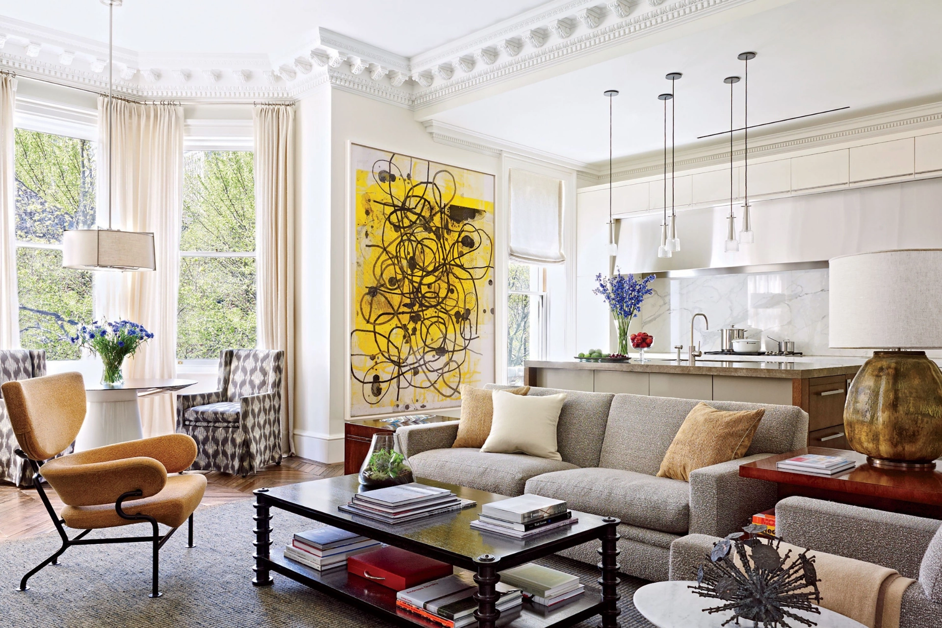 Elegant living room with a large yellow abstract painting, gray sofa, and kitchen with marble backsplash